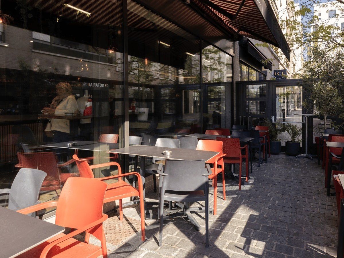 La terrasse couverte et vitrée, chaises orange et tables noires